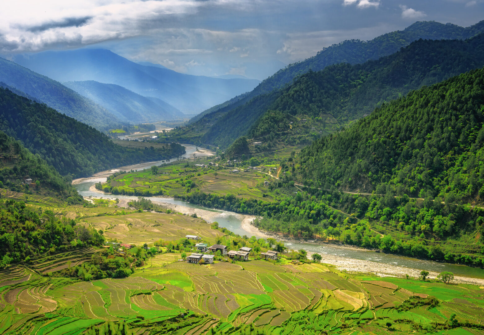 Valley in Bhutan near Punakha with rice fields and typical houses. Travel to Bhutan and enjoy the beautiful landscape of farms and mountains in this buddhist country.