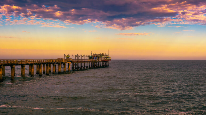 Colorful sunset over the old historic jetty in Swakopmund, Namibia. Swakopmund is situated in the Namib Desert and is the fourth largest population centre in Namibia.