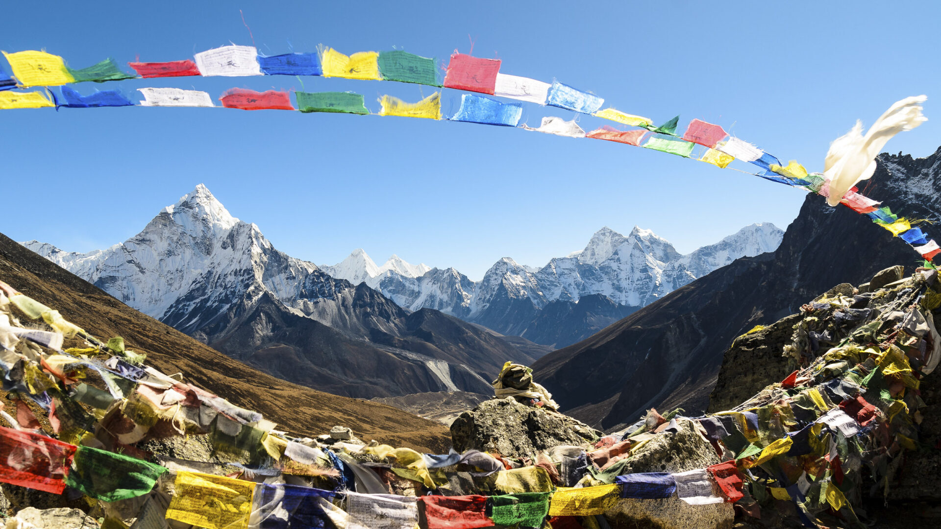 travel destinations off the beaten path: Himalayan mountain view with colored flags in Nepal