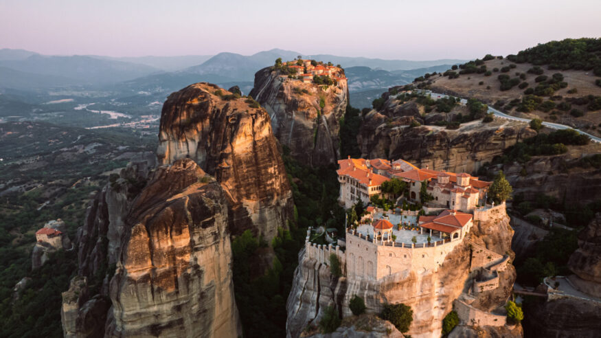 Aerial view of monasteries Trinity and breathtaking pictures of valley and landmark canyon of Meteora at sunset, Kalambaka, Greece, shadows, twisted road, bridge, Mountains as columns