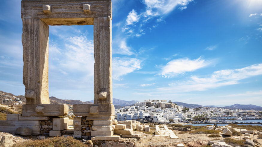 The famous gate of Naxos island, so called Portara from the temple of Apollon, in front of the whitewashed houses of the city, without people, Cyclades, Greece